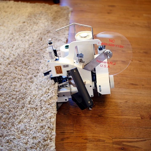 Portable carpet serger machine stitching the edge of a shag rug.